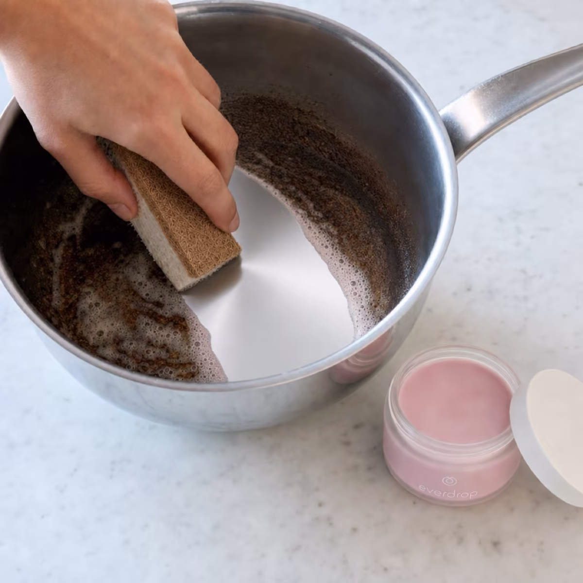 Pinke Putzsteinpaste wird mit einem Schwamm auf eine eingebrannte Fläche aufgetragen